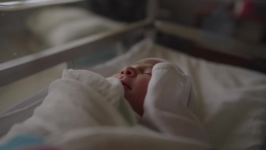 Newborn baby sleeping in hospital bed