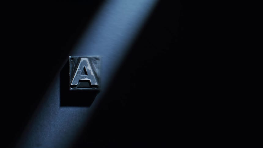 Closeup of a metallic letter a block dramatically lit against a dark background