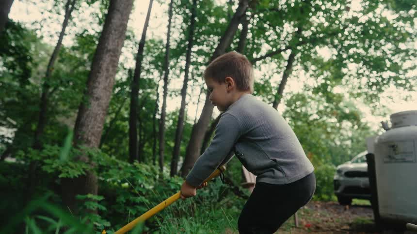 Boy with a shovel weeding a natural area