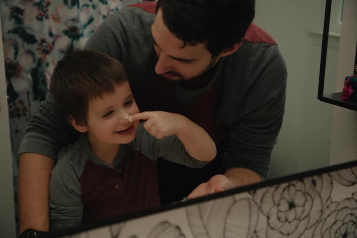 Father playing with his son in the bathroom with a mirror in front of him