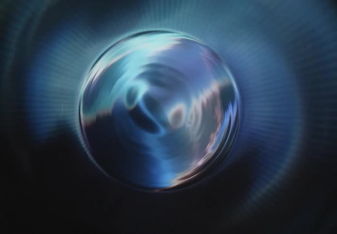 A shiny metallic sphere is centered within a radial pattern of ridges