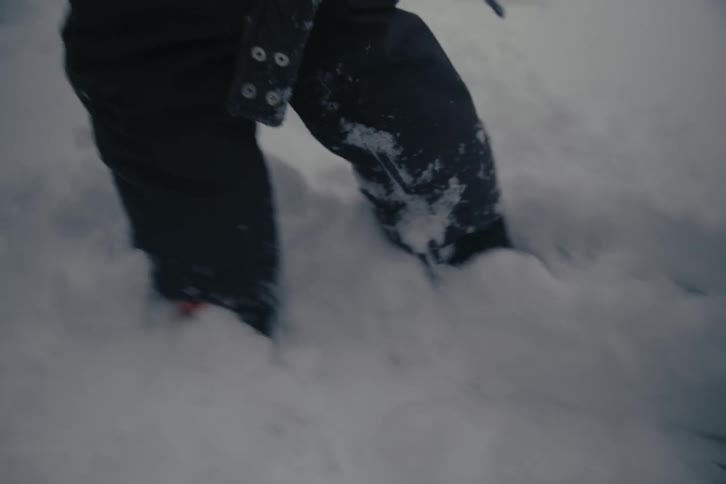 A child trudges through deep snow wearing snow gear