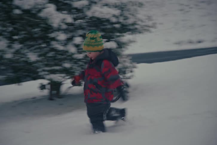 Young boy runs through deep snow in a quiet suburban winter landscape