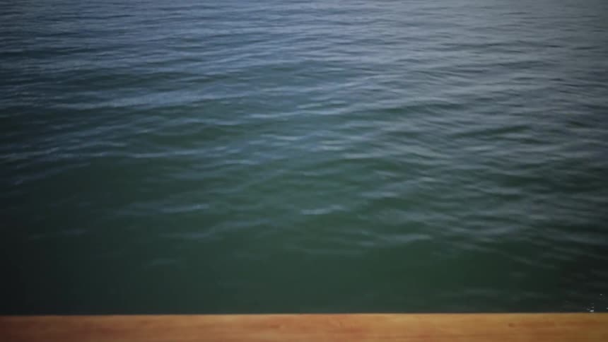 View of a boat moving across an ocean with mountains in the background