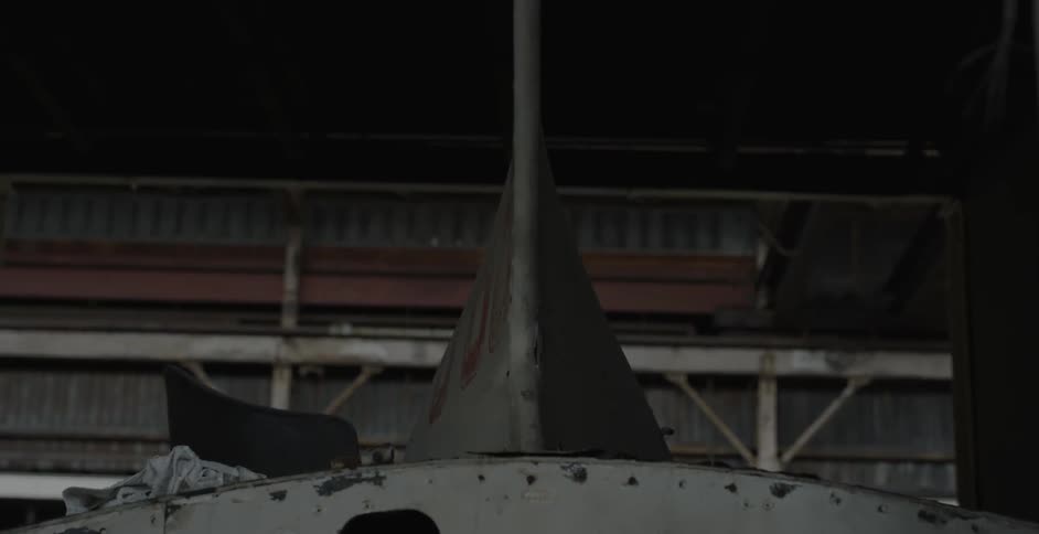 The hull of a ship sits in a warehouse
