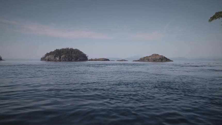 Landscape of a calm ocean with rocky islands in the background