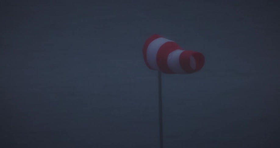 Orange and white windsock blowing in the wind at night
