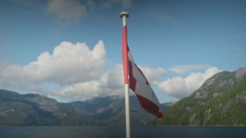 Canadian flag against a landscape of mountains and sea
