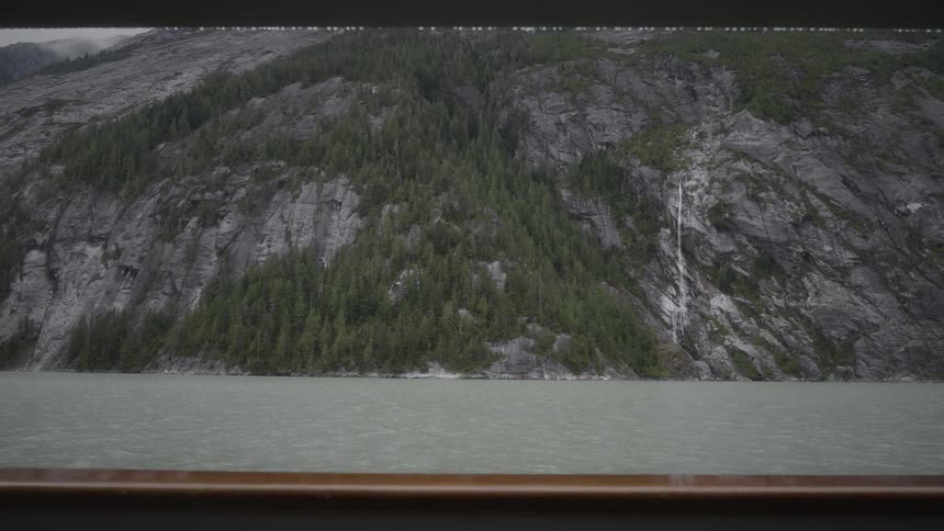 Landscape of an ocean with a mountain with conifers in the background