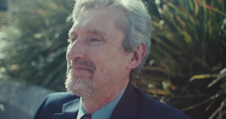 Man laughing while looking at phone outdoors