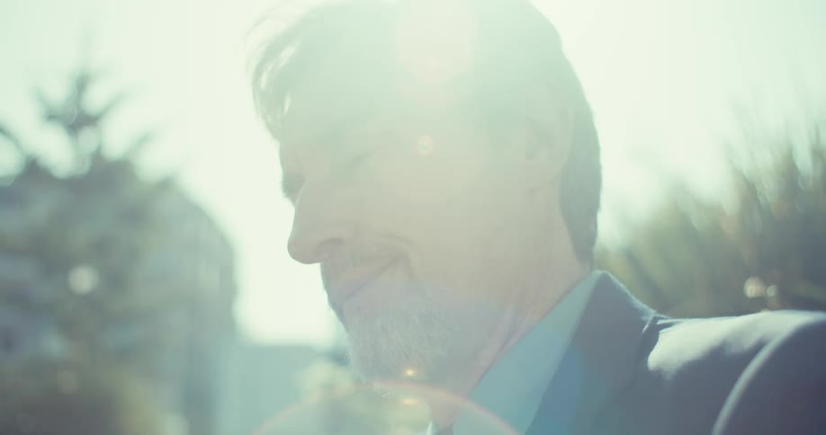 Man in suit sitting outdoors thoughtfully interacting with a smartphone