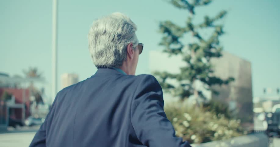 Man in suit walking on street and talking on smartphone