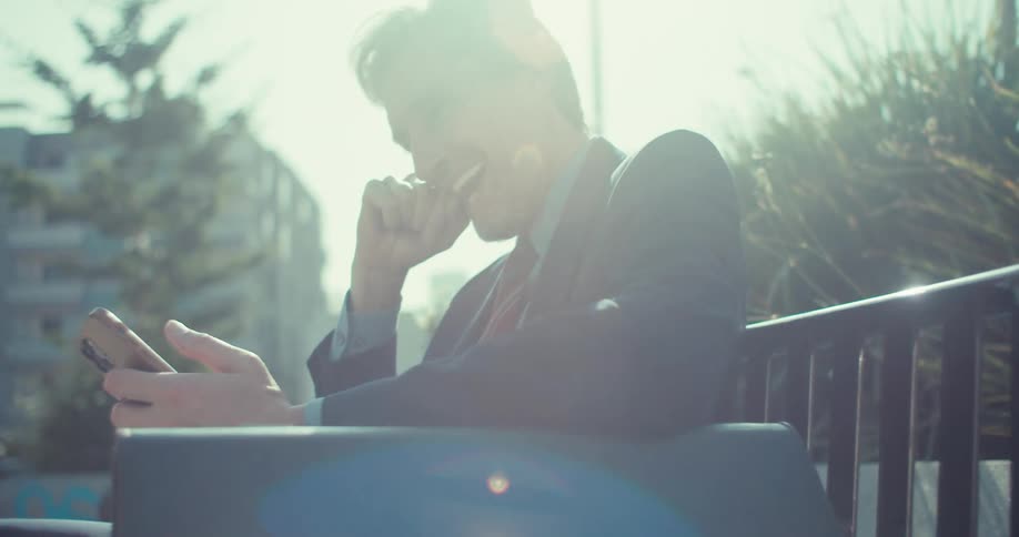 Man in a suit sitting interacting with a smartphone