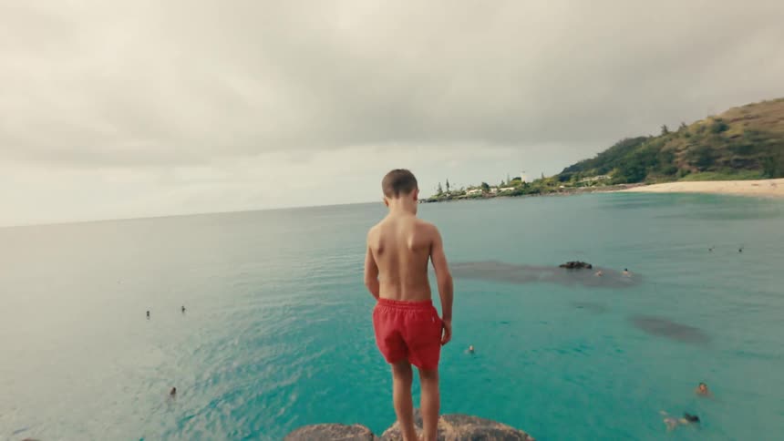Young boy leaps from cliff into ocean, conquering fear