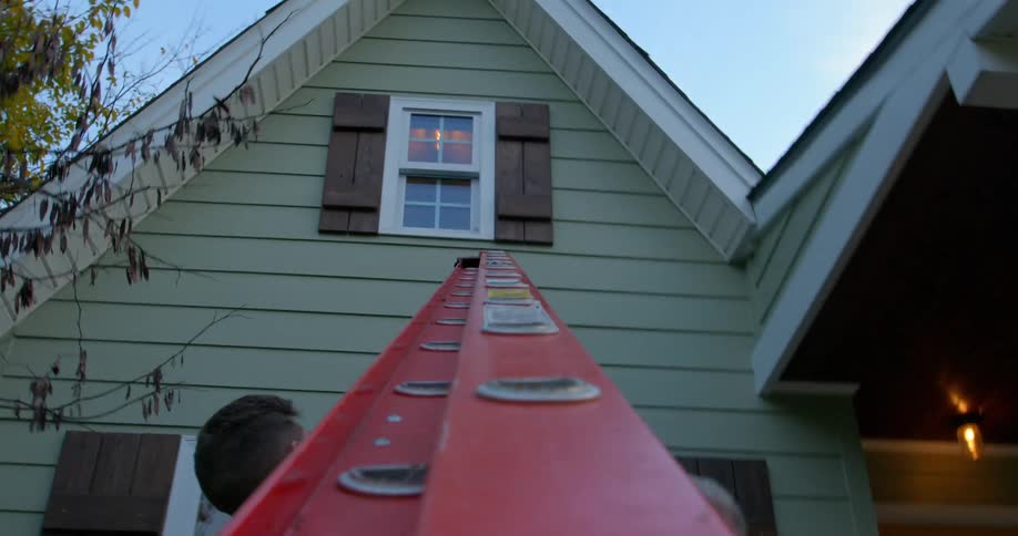 Two men carry a ladder to the home