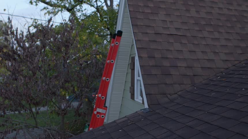 Leaning a tall red ladder under the eaves of a house near a small window