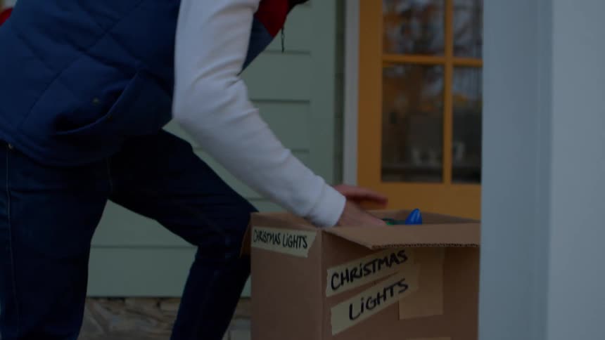 Man taking christmas lights out of a box