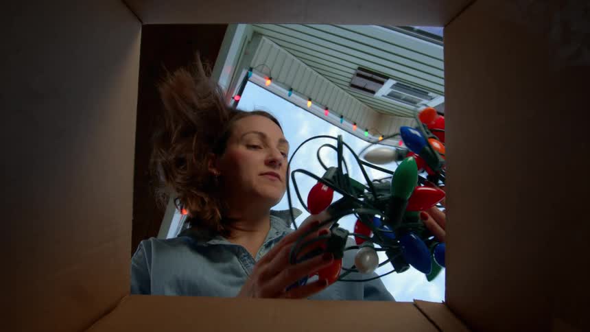 Woman picking up christmas lights from a box