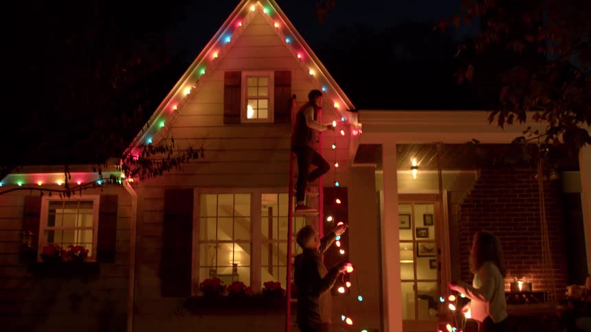 Family works together to put up christmas lights at night