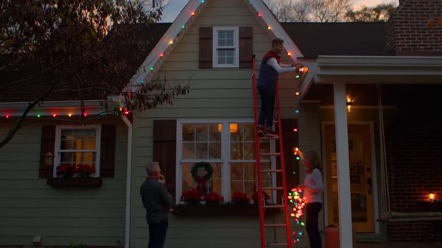 Family outside their home installing christmas lights