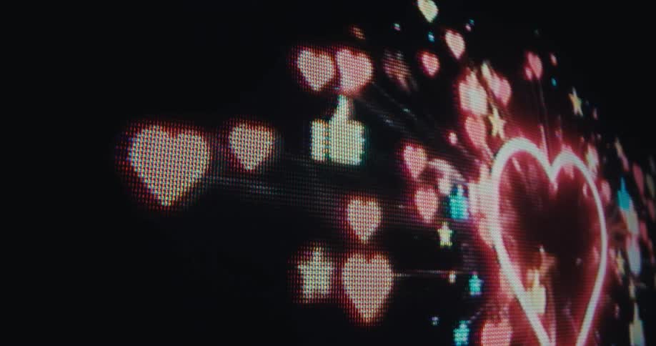 A screen displays digital hearts thumbsup and stars floating in a dark space