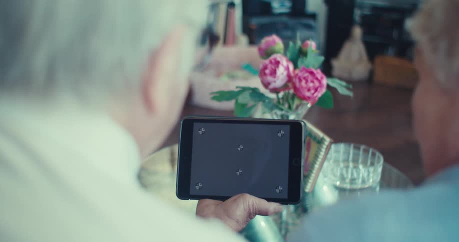 Elderly couple video calling on a tablet at home