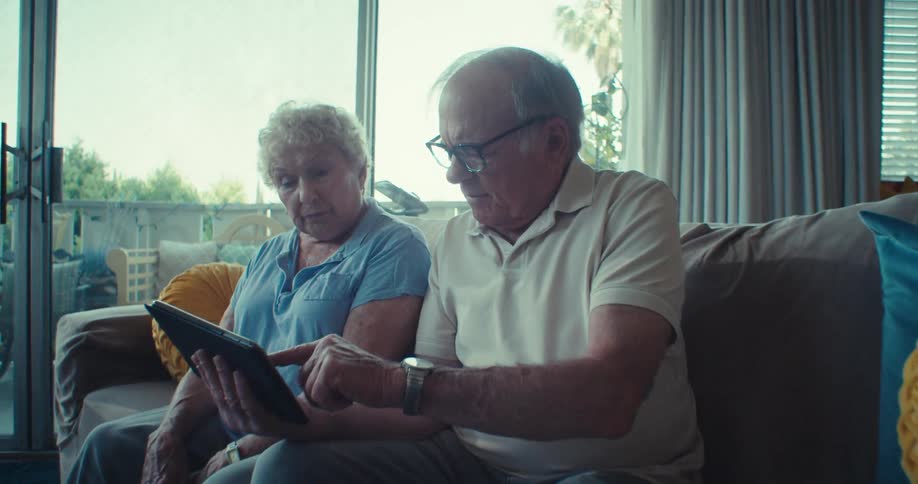 Elderly couple sitting on a sofa looking at a tablet together
