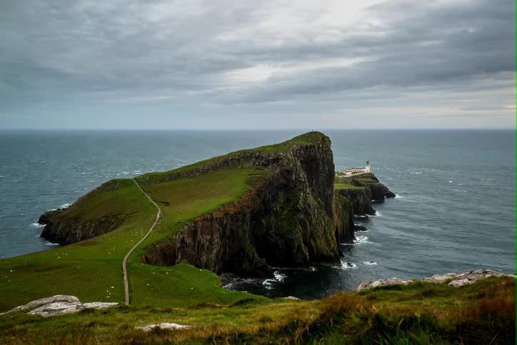 A view of a road going over a little piece of land leading to a lighthouse and is in timelapse
