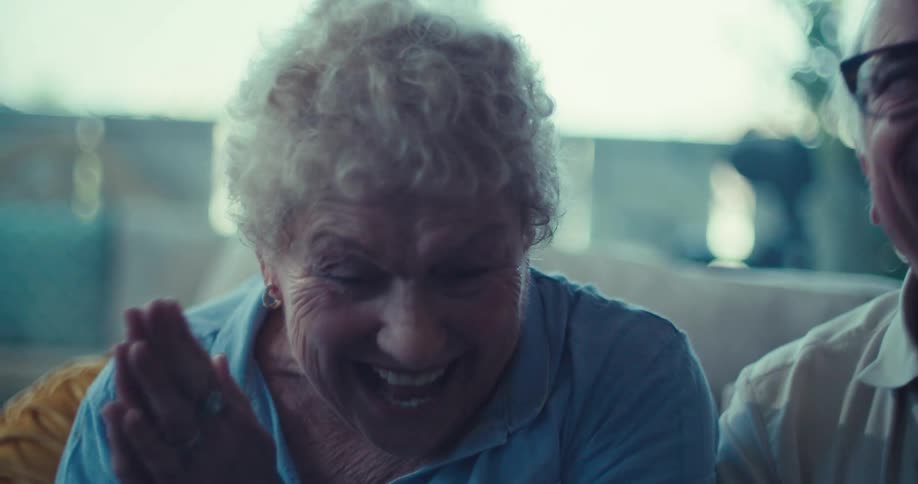 Two elderly people sitting in the living room laughing