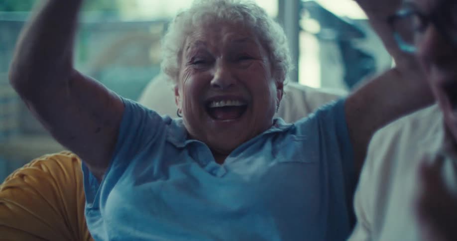 A joyful elderly couple celebrates while looking at a tablet on the couch