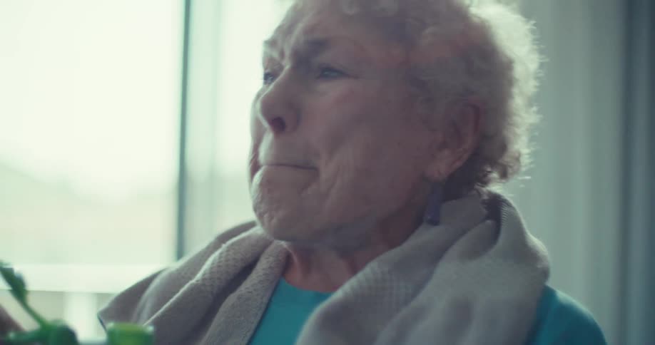 Elderly woman reacts expressively while holding a water bottle and talking post workout