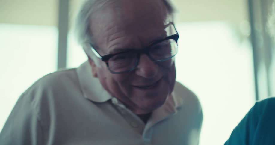 An elderly female using an exercise bike smiling as an elderly man watches her
