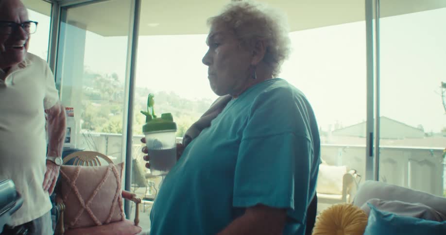 Elderly woman drinks water on exercise bike indoors