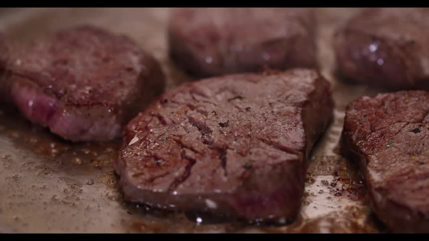 Several thick filets of steak sear to perfection on a hot pan