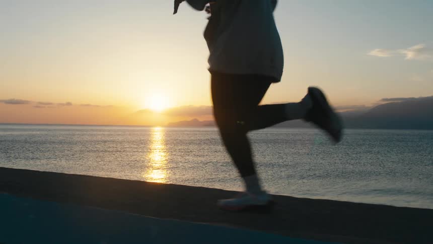 Running along the coastline as the sun rises on the horizon over the ocean