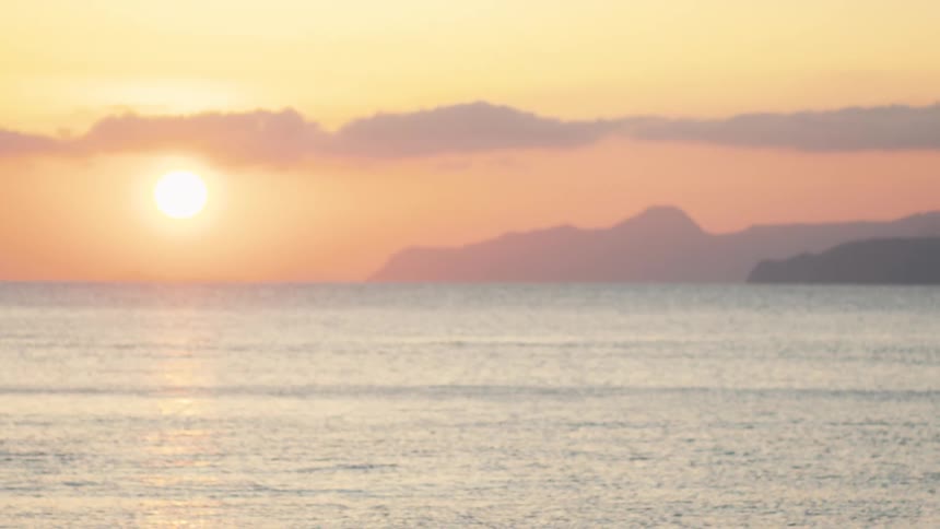 Legs of a person walking in the foreground and the ocean landscape in the background