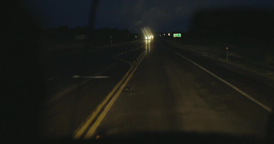 Vehicle drives on the highway while it drizzles at night