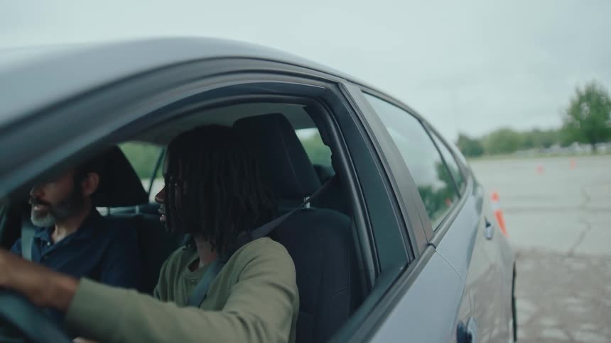 A driving instructor and student focus during a practice session in a parked car