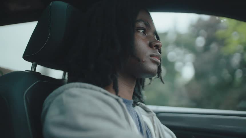 A focused young man drives a car eyes fixed ahead