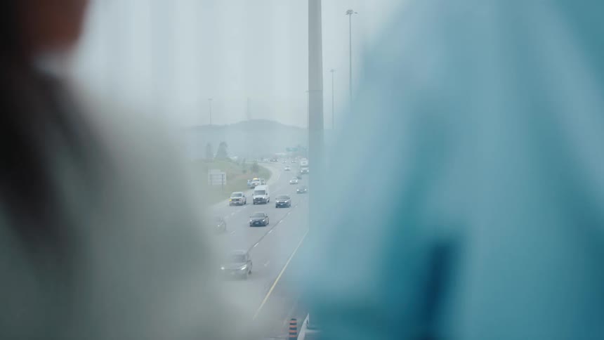 A highway is seen in the distance between two blurred figures