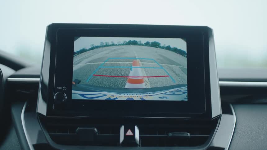 Close up of a rearview dashboard monitor displaying a driver hitting a cone