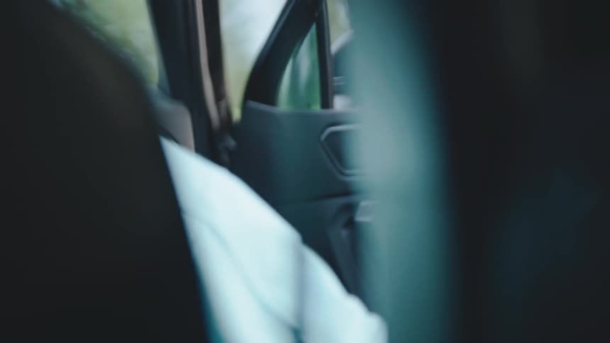 A woman opens the passengerside door of a car and steps out into the midday light