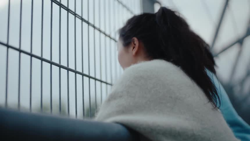 Two females leaning on a fence outdoors and chatting