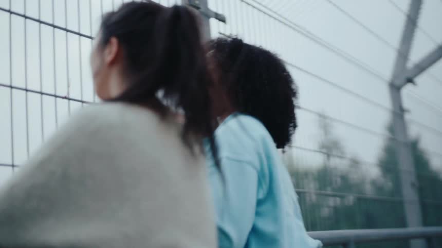 Friends leaning on a railing of an overpass talking