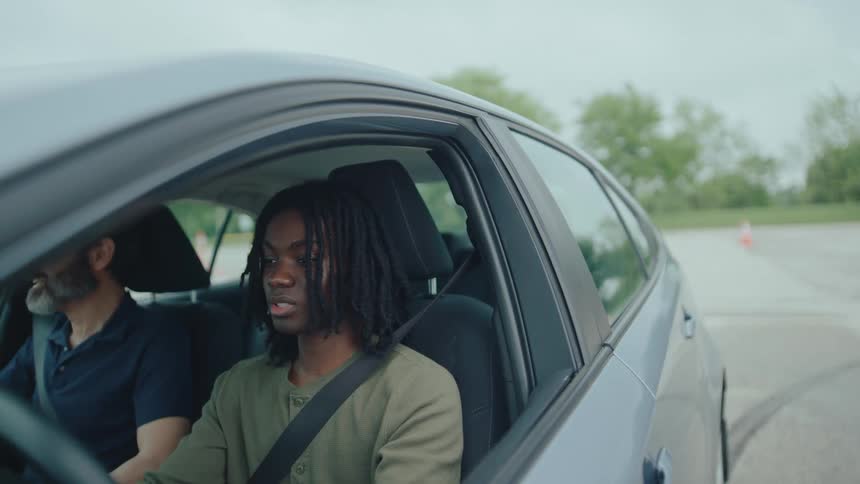 The instructor talks to the teenager as he drives