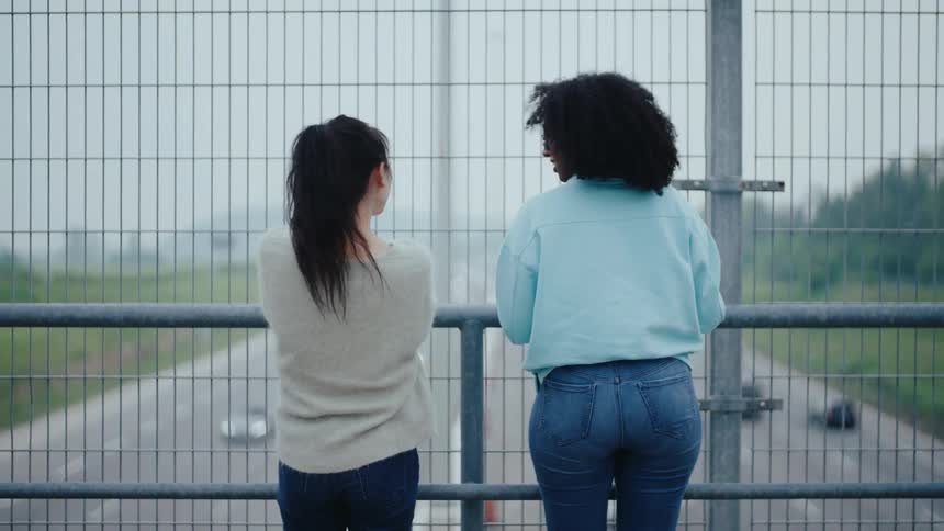 Two women on an overpass on a cloudy day