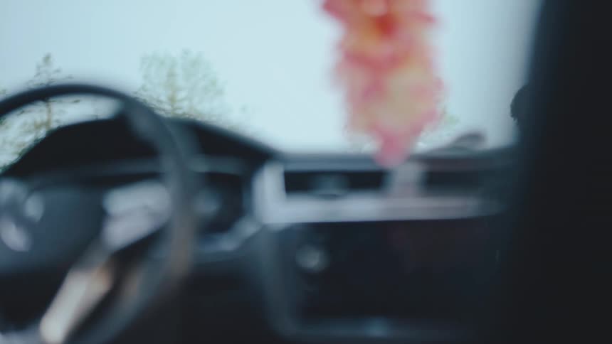 Two people smile and talk outside seen through the blurry interior of a car