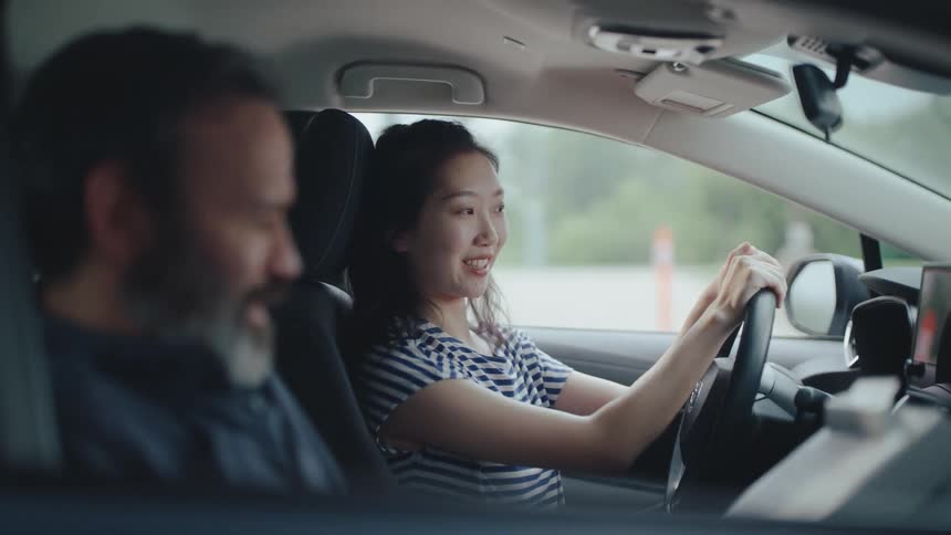Examiner talking to a woman who is behind the wheel of a car