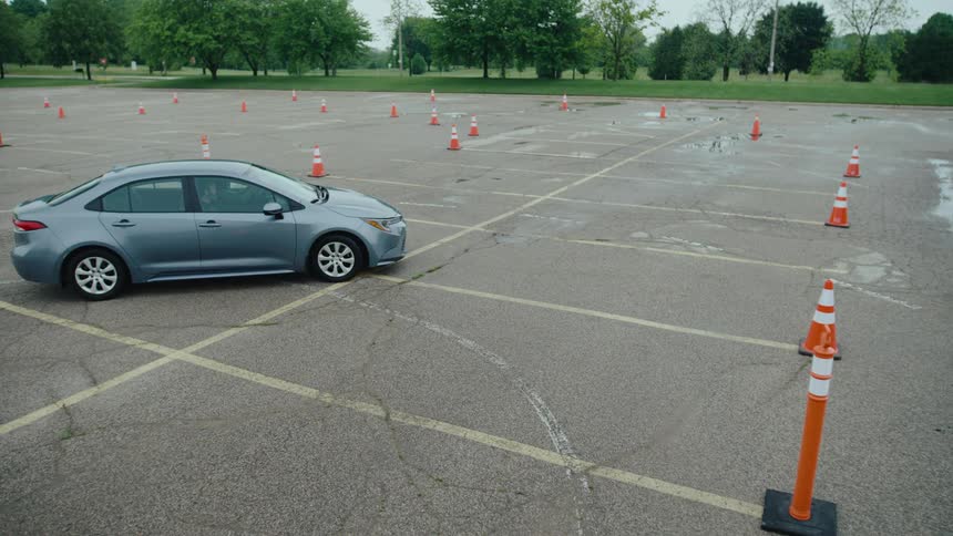 A car carefully drives between traffic cones during a parking lot test
