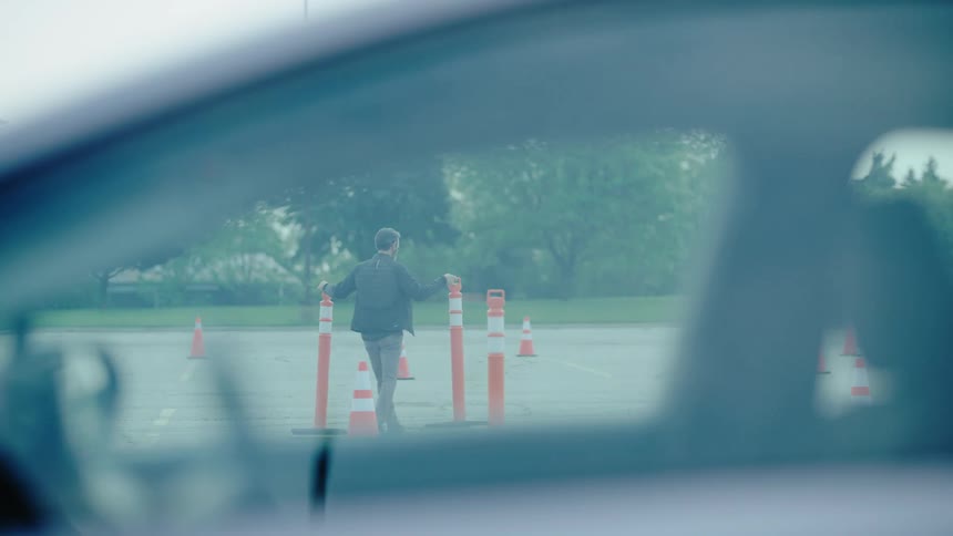A man is placing traffic cones in the parking lot